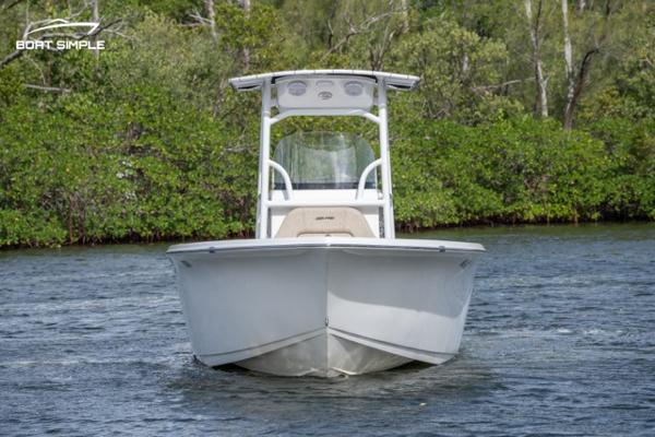 Slide: The Image of 2023 Sea Pro 219 Deep V CC boat on water, front view, with lush greenery in background. - 1