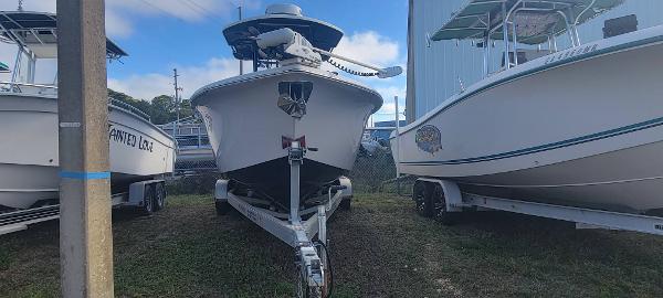 Slide: The Image of 2020 Sea Pro 239CC boat on a trailer, parked between two other boats. - 1