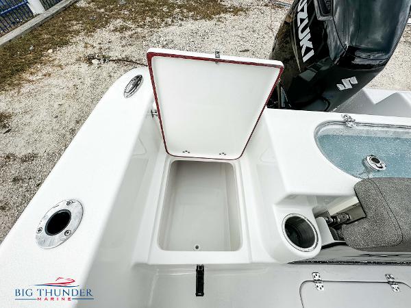 Slide: The Image of 2023 Sea Pro 239 DLX boat with open storage compartment and Suzuki engine. - 23