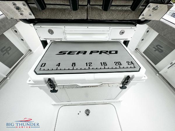 Slide: The Image of 2023 Sea Pro 239 DLX boat interior with branded cooler and storage compartments. - 26