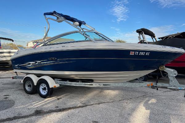 Slide: The Image of 2004 Sea Ray 200 Select boat on trailer, blue and white design, parked outdoors. - 0