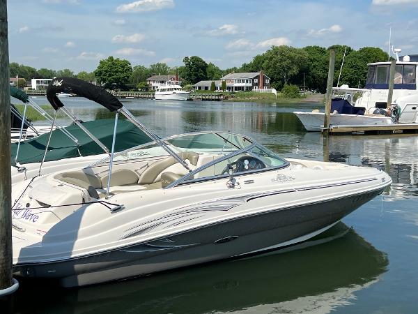 Slide: The Image of 2006 Sea Ray 200 Sundeck boat docked on a calm lake with scenic background. - 1