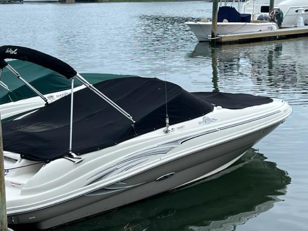Slide: The Image of 2006 Sea Ray 200 Sundeck boat docked with black cover on calm water. - 11