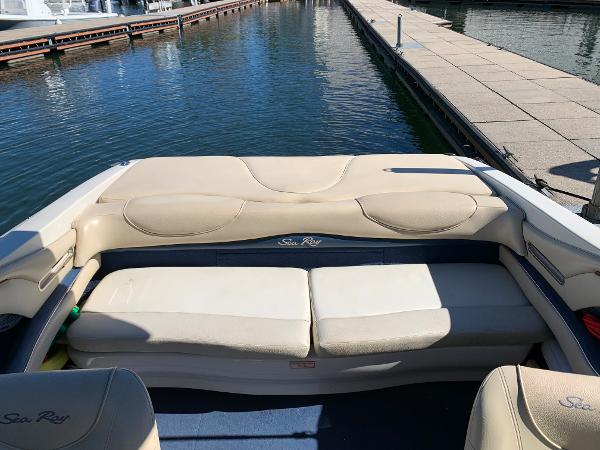 Slide: The Image of 2000 Sea Ray 210 Bow Rider boat interior with beige seating at a marina. - 15