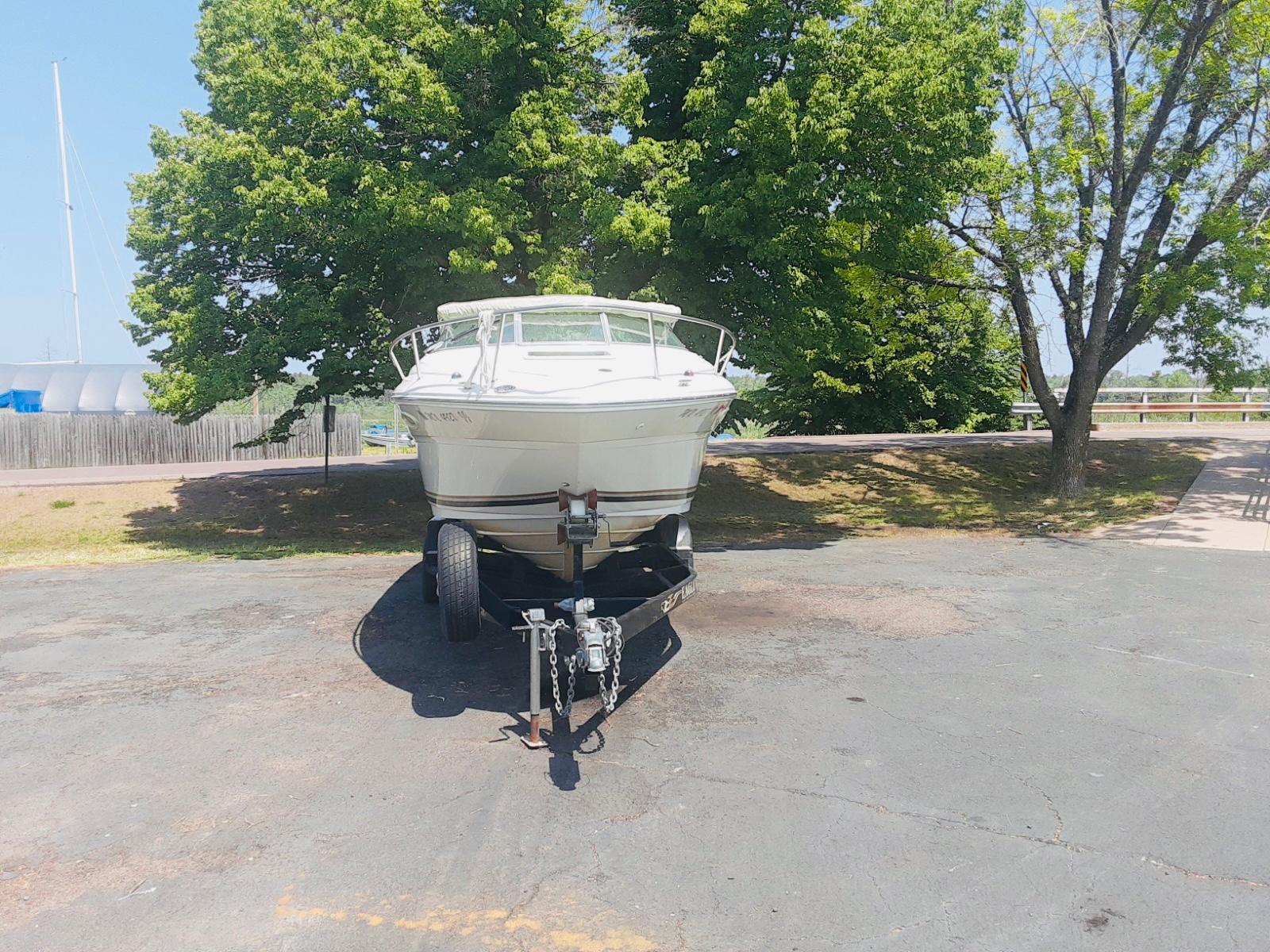 Slide: The Image of 2001 Sea Ray 225 Weekender boat on trailer, parked near trees. - 1