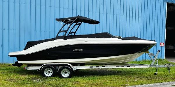 Slide: The Image of 2024 Sea Ray 230 SPX boat on a trailer, parked near a blue building. - 1