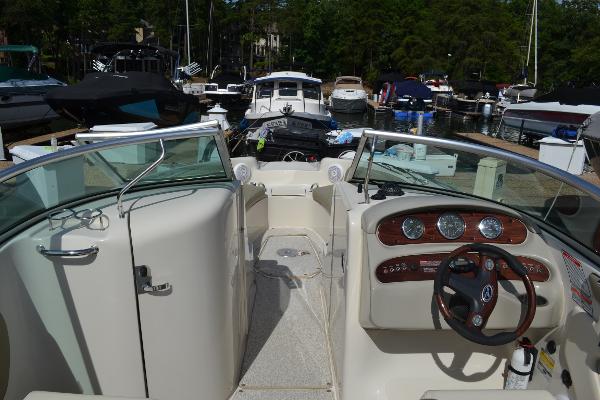 Slide: The Image of 2005 Sea Ray 240 Sundeck boat interior at marina, featuring dashboard and seating area. - 8