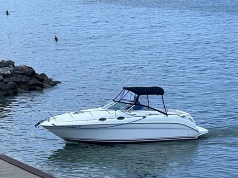 Slide: The Image of 2001 Sea Ray 260 Sundancer boat cruising on calm waters near a rocky shore. - 13