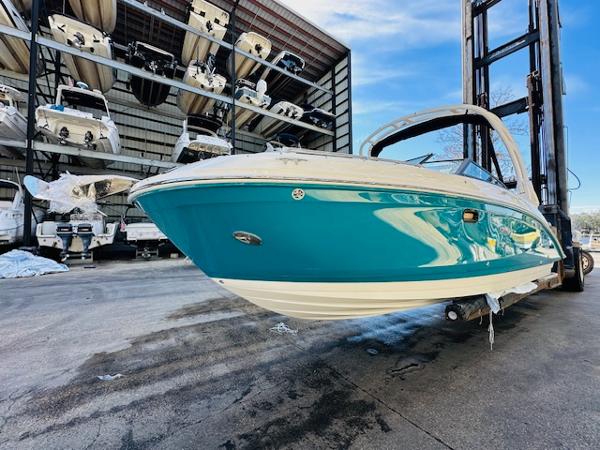 Slide: The Image of 2025 Sea Ray 270 SDX boat in storage, vibrant blue hull, marina background. - 2