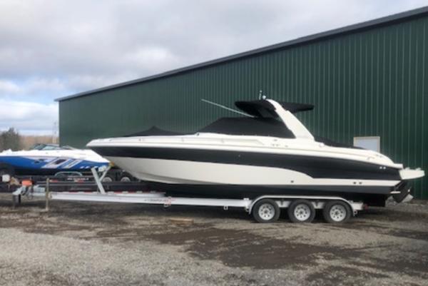 Slide: The Image of 2000 Sea Ray 280 Bow Rider on trailer, parked outdoors near a green building. - 0