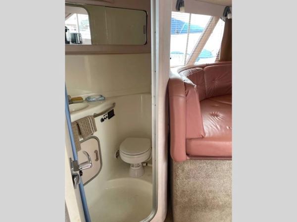 Slide: The Image of 1989 Sea Ray 300 Sedan Bridge interior with bathroom and seating area. - 17