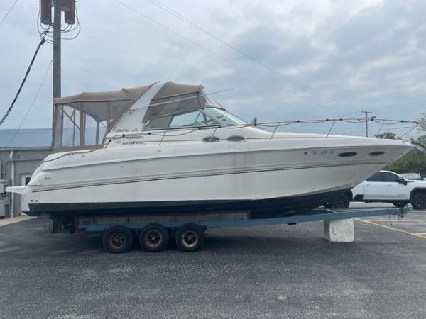 Slide: The Image of 1999 Sea Ray 310 DA boat on a trailer in a parking lot. - 0