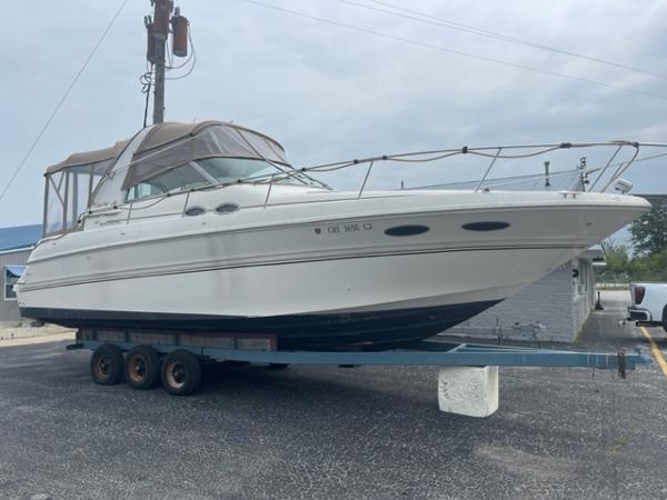 Slide: The Image of 1999 Sea Ray 310 DA boat on a trailer in a parking lot. - 1