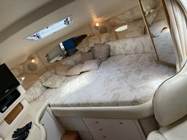 Slide: The Image of 1999 Sea Ray 310 Sundancer cabin interior with bed, TV, and storage cabinets. - 2