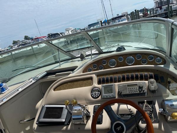 Slide: The Image of 1999 Sea Ray 310 Sundancer boat dashboard and controls at a marina. - 5