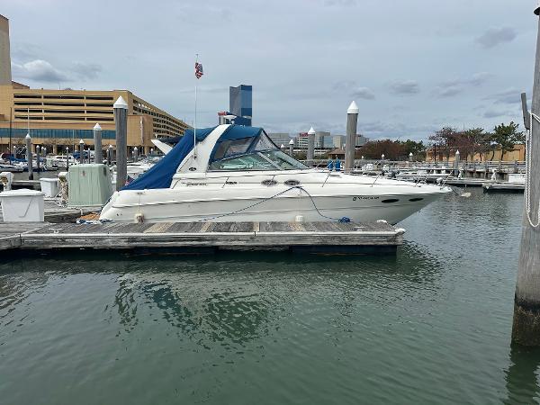 Slide: The Image of 2002 Sea Ray 310 Sundancer docked at a marina with cityscape background. - 0