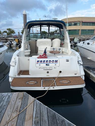 Slide: The Image of 2002 Sea Ray 310 Sundancer docked at marina, rear view with American flag. - 4