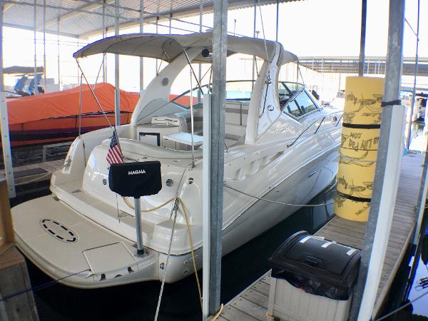 Slide: The Image of 2002 Sea Ray 320 Sundancer docked in a marina, featuring sleek design and American flag. - 2