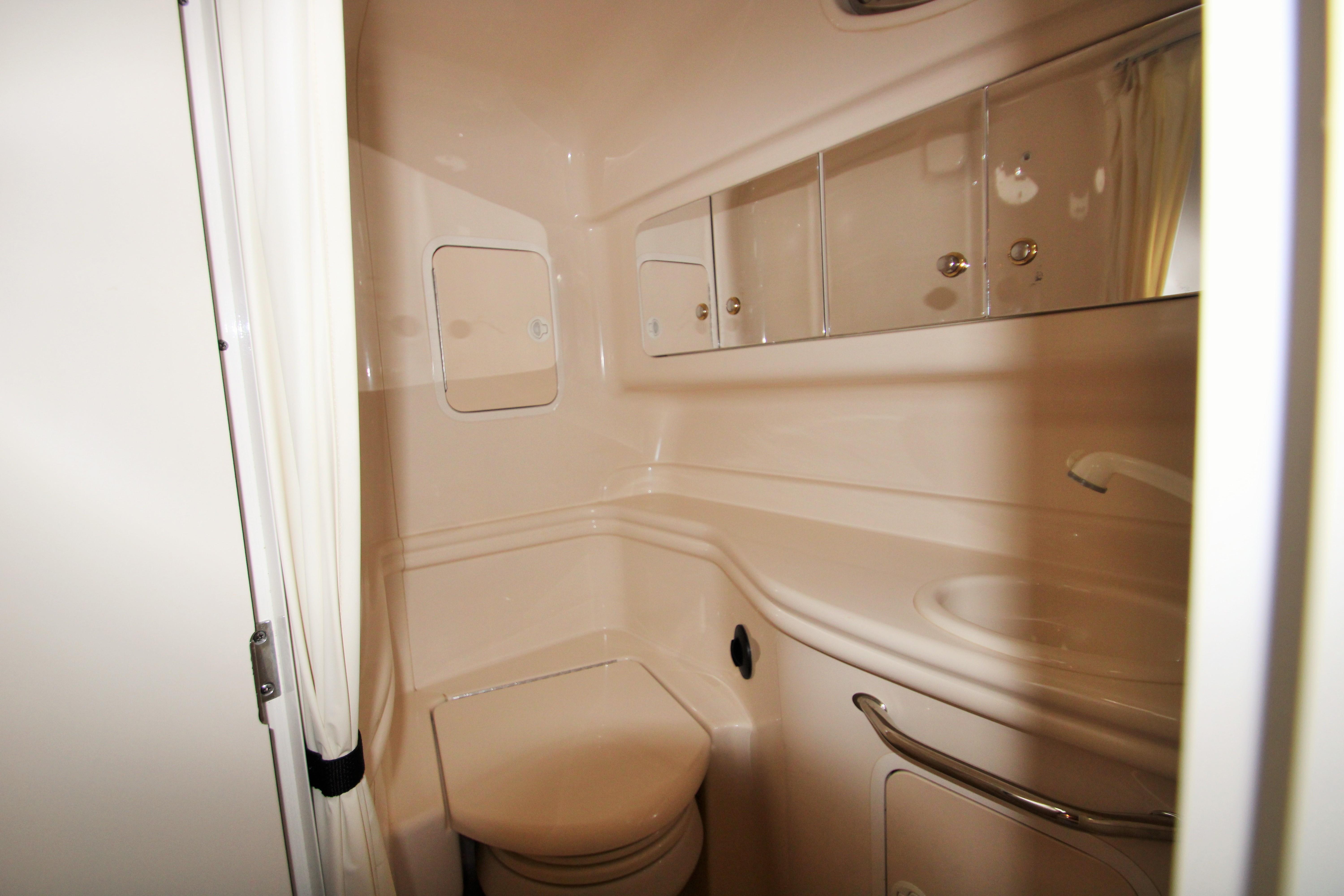 Slide: The Image of 2003 Sea Ray 320 Sundancer bathroom with compact design and mirrored storage. - 15