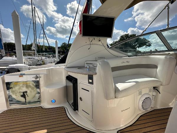 Slide: The Image of 2004 Sea Ray 320 Sundancer boat interior with seating, TV, and marina view. - 14