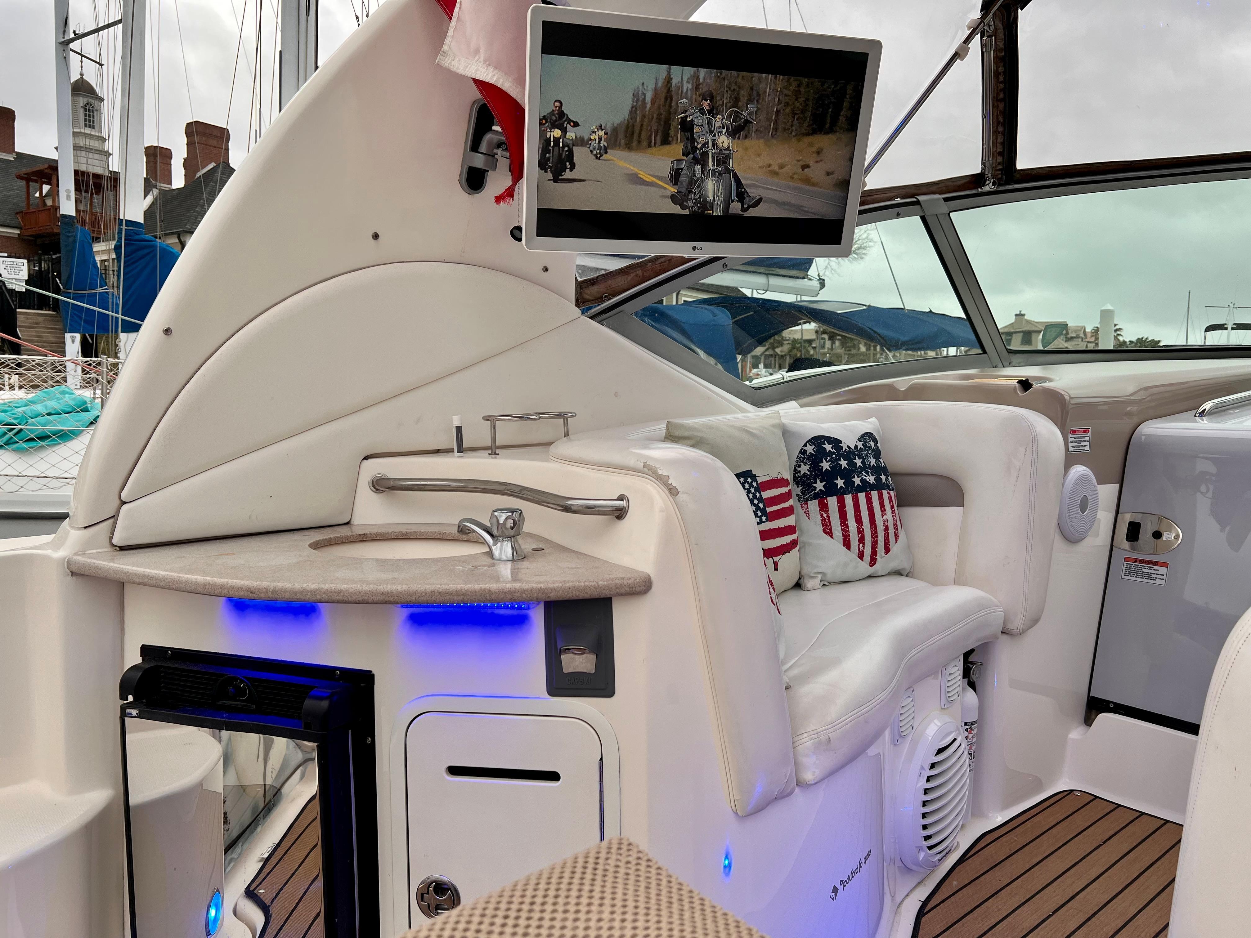Slide: The Image of 2004 Sea Ray 320 Sundancer interior with TV, sink, and patriotic pillows. - 15