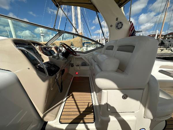 Slide: The Image of 2004 Sea Ray 320 Sundancer cockpit with helm, white seating, and wooden flooring. - 19