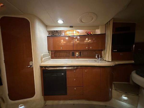 Slide: The Image of 2004 Sea Ray 320 Sundancer galley with wooden cabinets and modern appliances. - 33