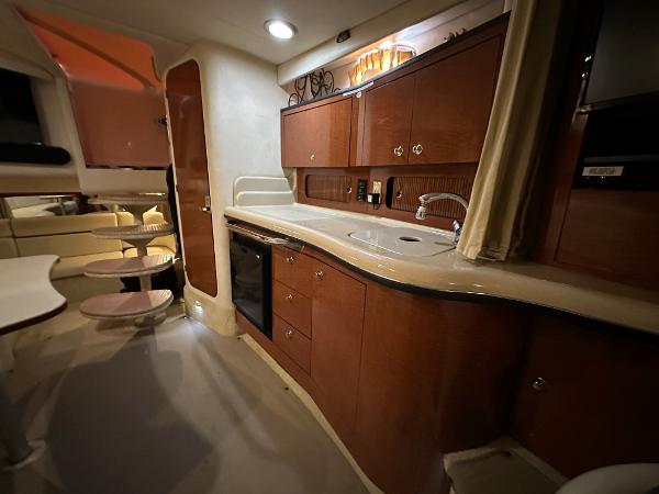 Slide: The Image of 2004 Sea Ray 320 Sundancer interior kitchen with wooden cabinets and modern amenities. - 38