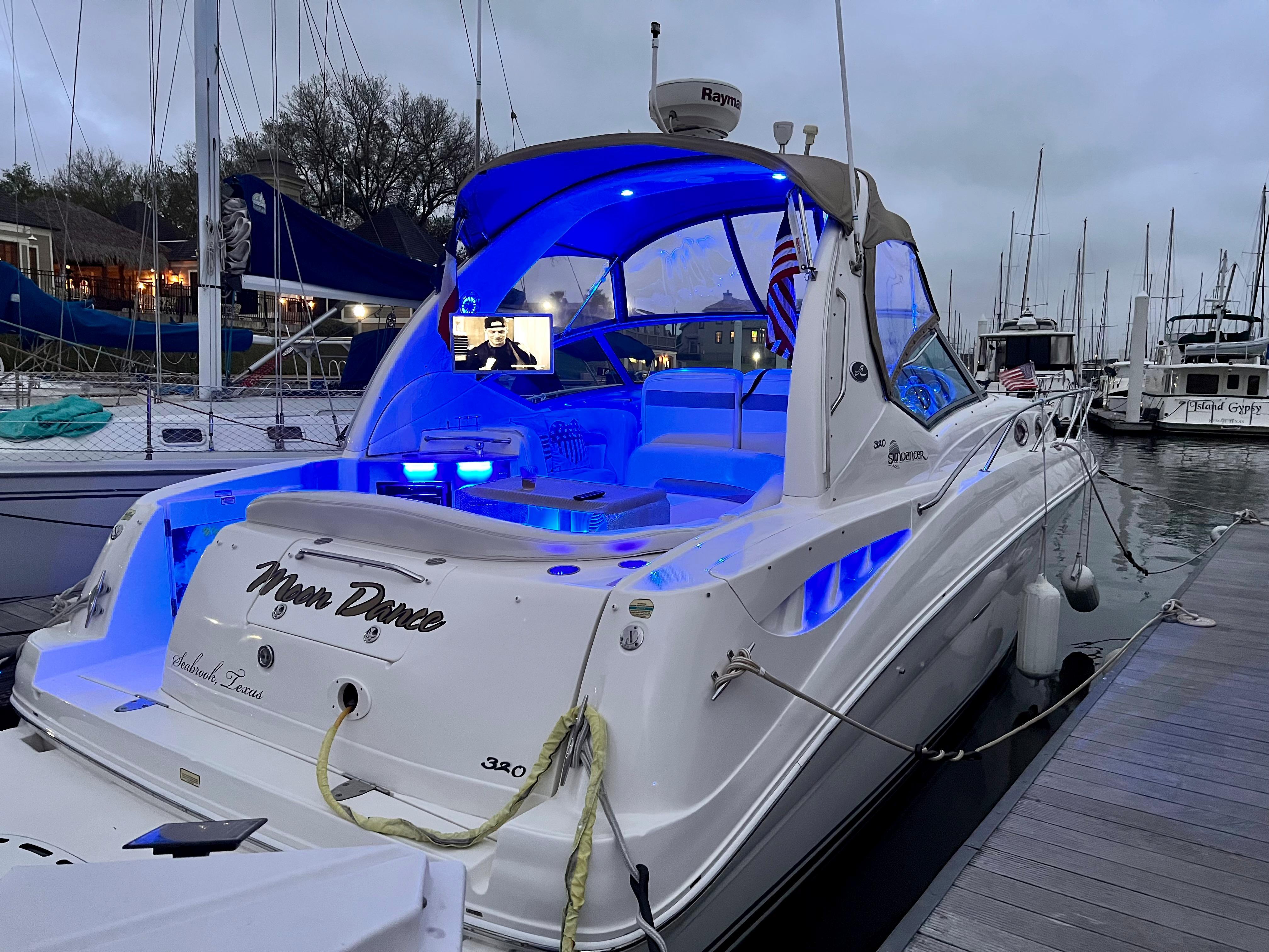 Slide: The Image of 2004 Sea Ray 320 Sundancer docked with blue interior lights at a marina. - 7