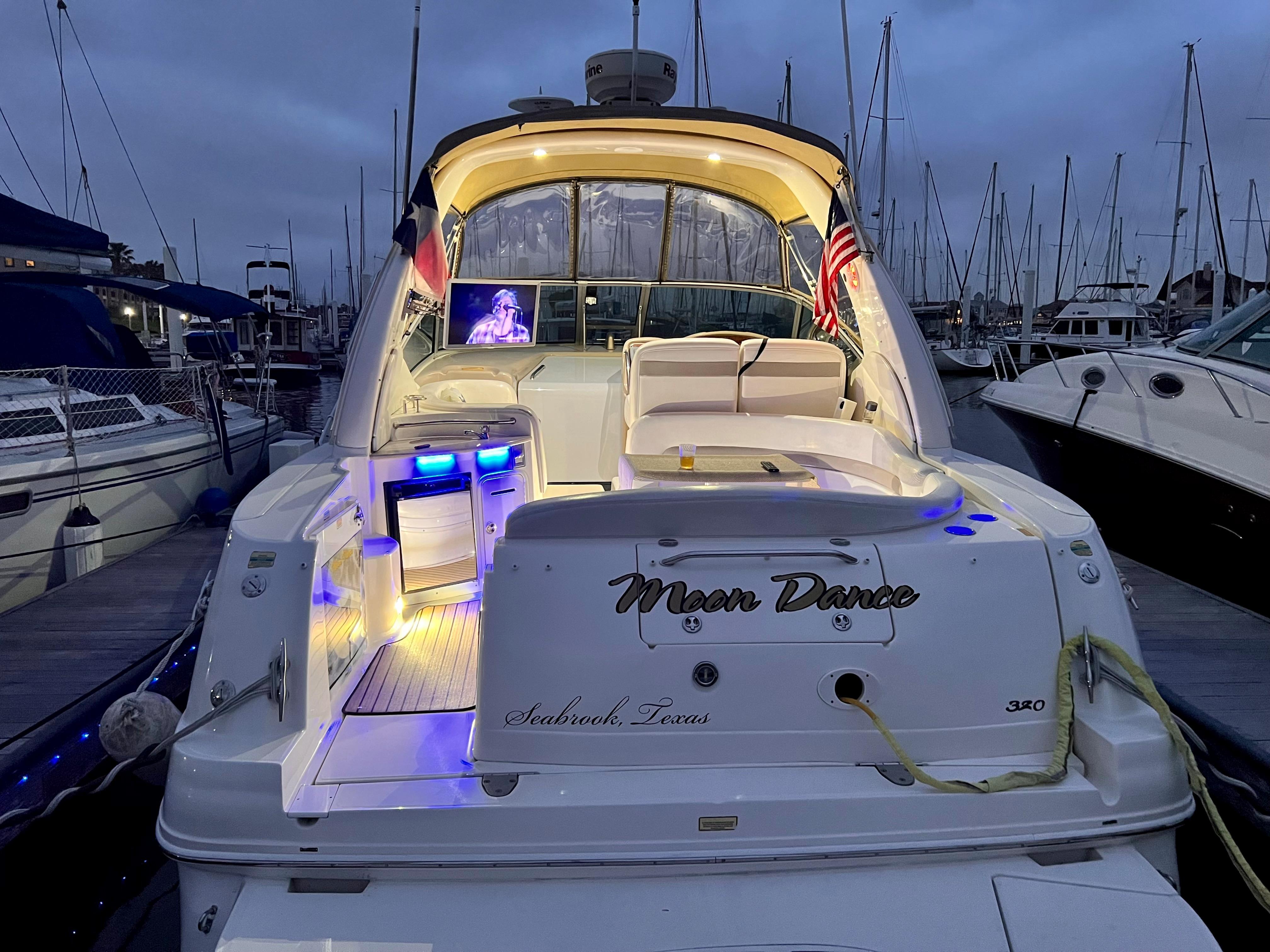 Slide: The Image of 2004 Sea Ray 320 Sundancer yacht docked at marina, illuminated deck, Moon Dance name visible. - 9