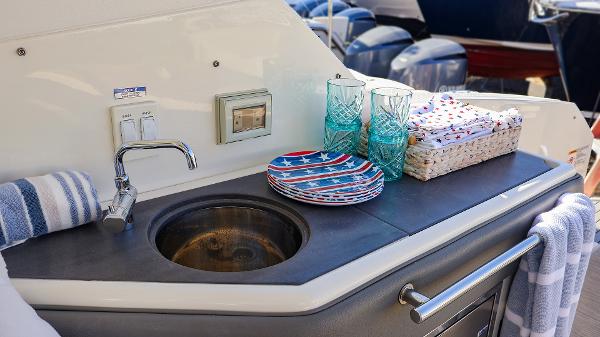 Slide: The Image of Outdoor sink area on 2021 Sea Ray 320 Sundancer yacht with plates and glasses. - 27