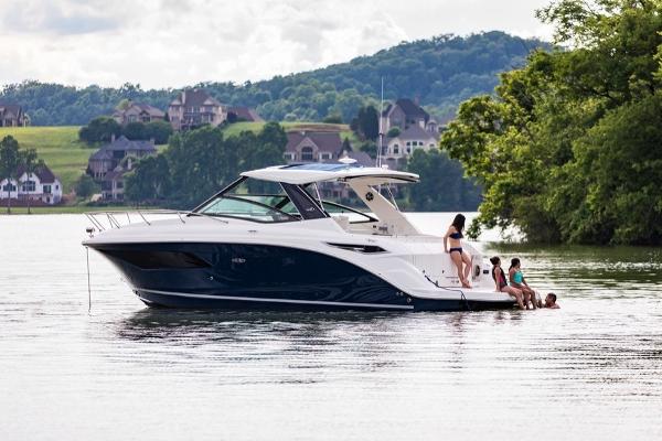 Slide: The Image of 2023 Sea Ray Sundancer 320 yacht on a serene lake with people enjoying the water. - 6