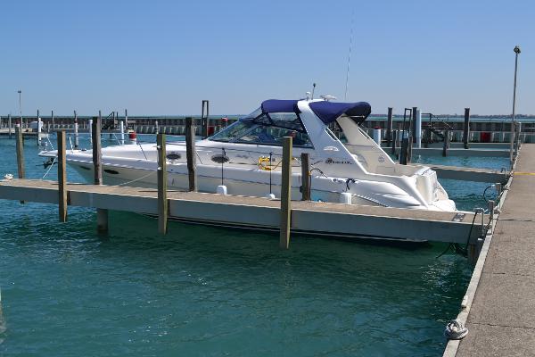 Slide: The Image of 1998 Sea Ray 330 Sundancer docked at marina, blue canopy, calm water, clear sky. - 0