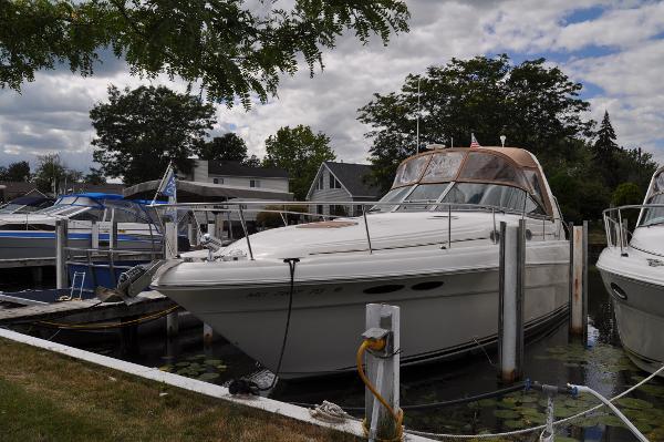 Slide: The Image of 1999 Sea Ray 340 Sundancer docked at marina, surrounded by trees and other boats. - 0