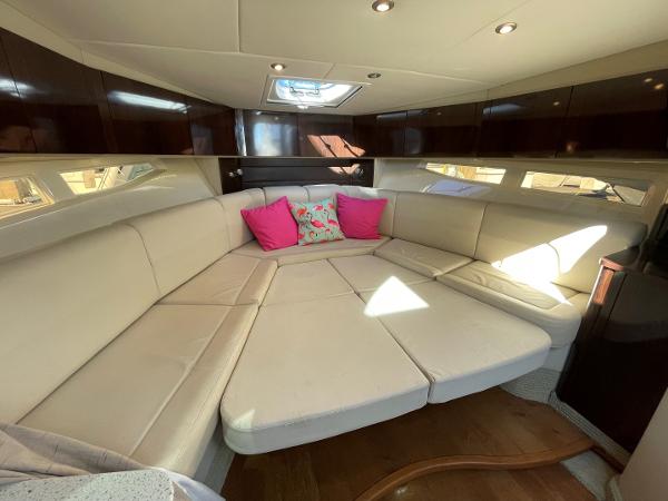 Slide: The Image of 2015 Sea Ray 370 Venture cabin with white leather seating and pink accent pillows. - 29
