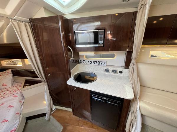 Slide: The Image of 2015 Sea Ray 370 Venture interior kitchen with microwave, stove, and bed. - 33