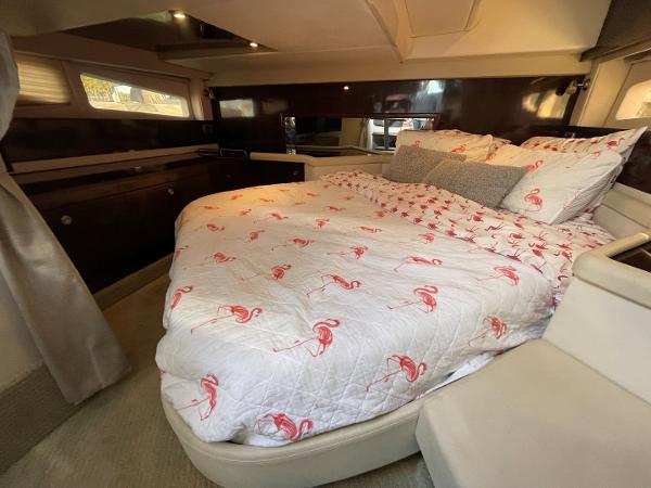 Slide: The Image of 2015 Sea Ray 370 Venture cabin with a cozy bed and flamingo-themed bedding. - 38