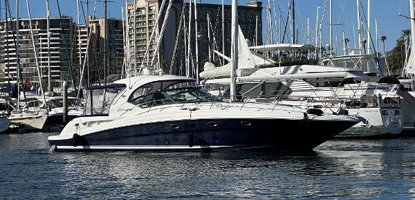 Slide: The Image of 2005 Sea Ray 420 Sundancer yacht docked in a marina with cityscape background. - 0
