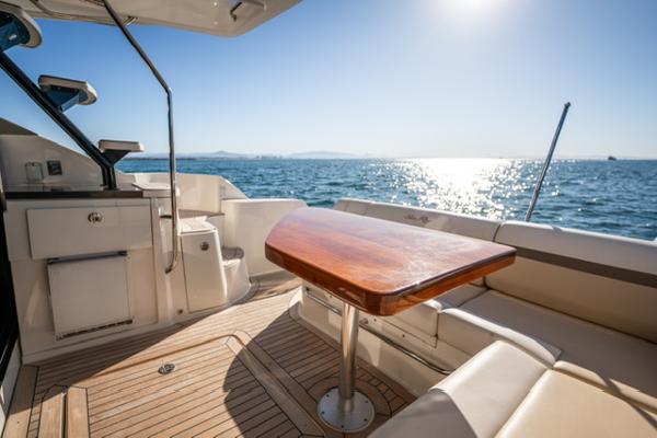 Slide: The Image of 2015 Sea Ray 510 Fly yacht deck with wooden table, ocean view, and sunny sky. - 5