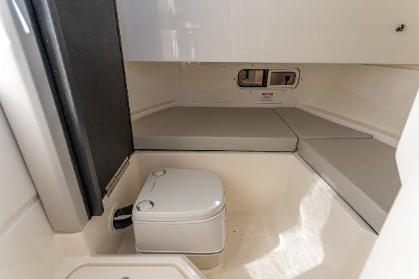 Slide: The Image of 2021 Sea Ray SDX 250 cabin interior with compact toilet and seating area. - 29
