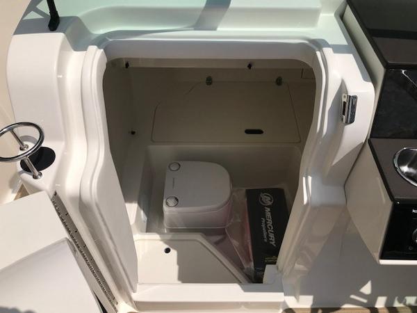Slide: The Image of 2025 Sea Ray SDX 250 boat interior with compact toilet and storage space. - 19