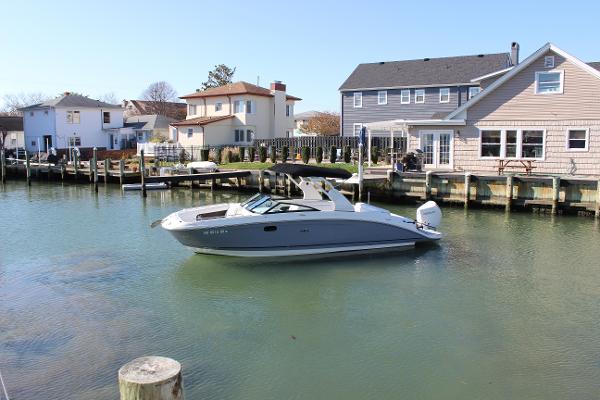 Slide: The Image of 2020 Sea Ray SDX 270 OB boat docked in a residential waterfront area. - 2