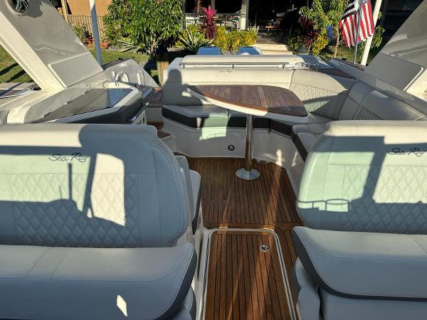 Slide: The Image of 2021 Sea Ray SLX 310 OB boat interior with cushioned seating and wooden table. - 16