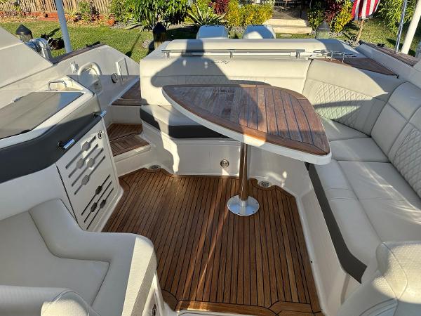 Slide: The Image of 2021 Sea Ray SLX 310 OB boat interior with wooden table and cushioned seating. - 18
