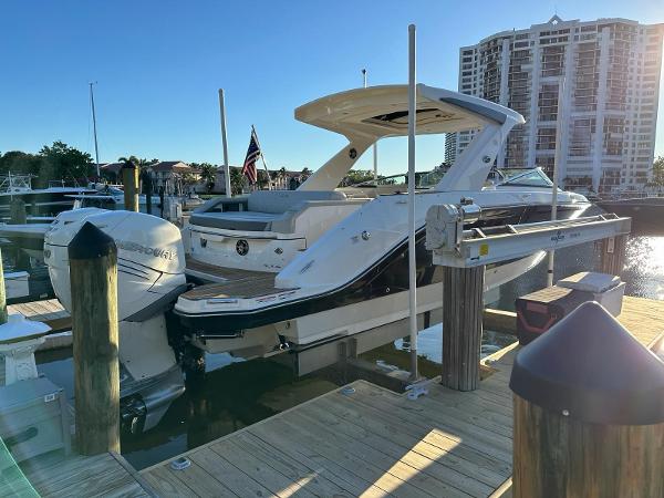 Slide: The Image of 2021 Sea Ray SLX 310 OB docked at a marina with a cityscape background. - 3