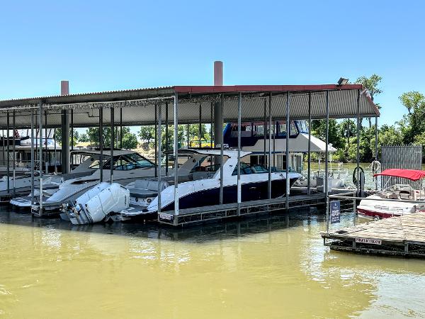 Slide: The Image of 2023 Sea Ray SLX 400 OB docked in a marina under a covered slip. - 2
