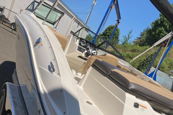 Slide: The Image of 2021 Sea Ray SPX 210 OB boat with beige interior, docked outdoors under clear blue sky. - 9