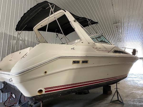Slide: The Image of 1990 Sea Ray Sundancer boat in storage, white hull with red stripes. - 0