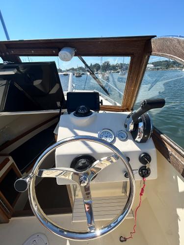 Slide: The Image of 2021 Seaway 21 Seafarer Cuddy boat helm with steering wheel and controls, on a sunny day. - 11