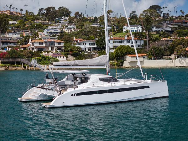 Slide: The Image of 2024 Seawind 1600 catamaran sailing near coastal homes. - 0
